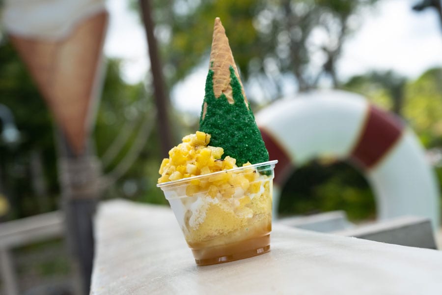 DOLE Whip and vanilla soft-serve swirl served over vanilla cake with caramelized pineapple, a cherry, and white chocolate-dipped cone