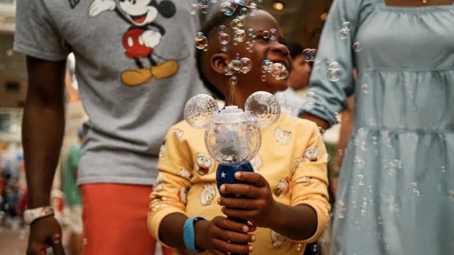A happy young boy holding a Mickey Mouse shaped bubble maker