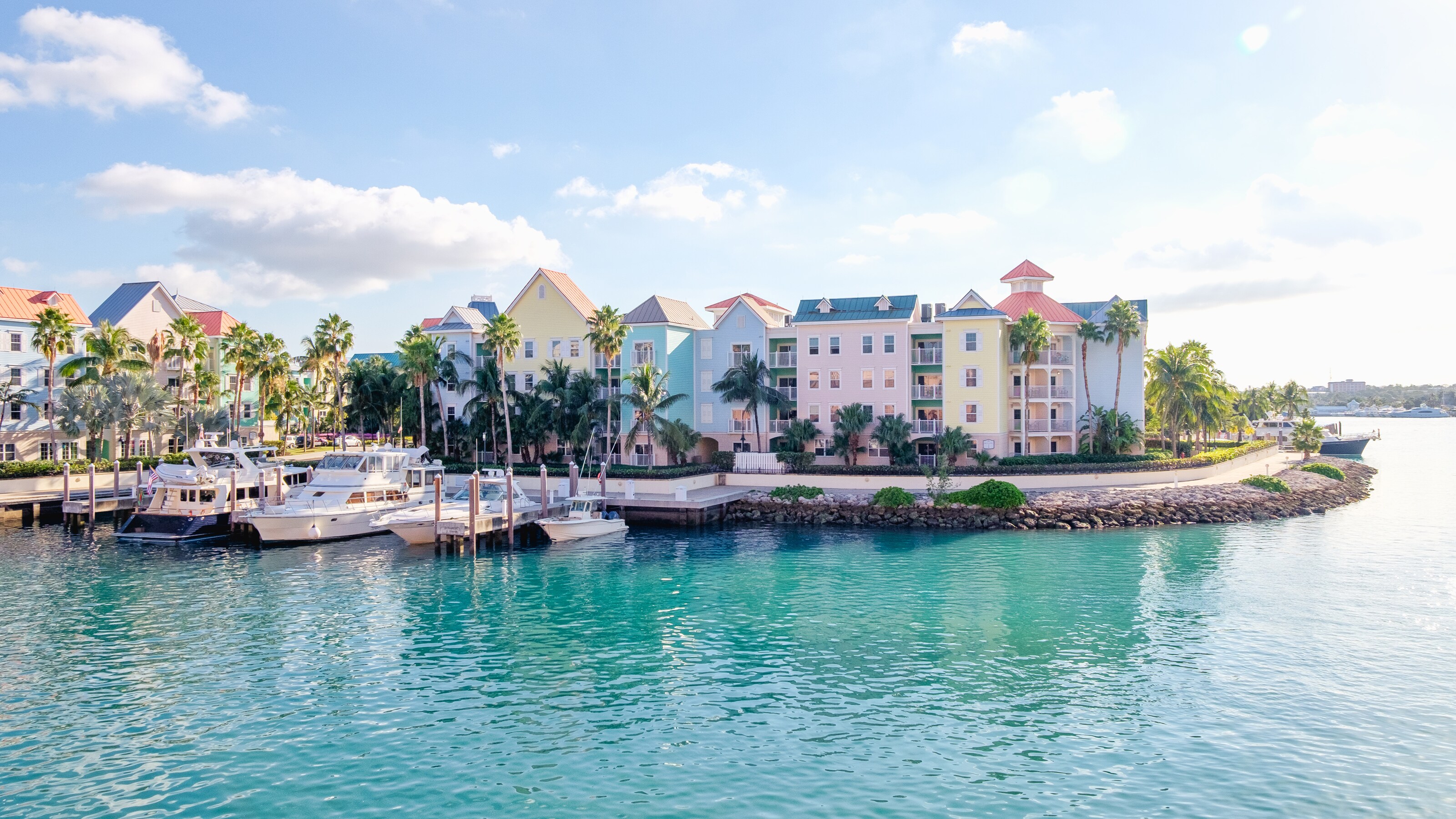 Boats docked in a harbor in front of colorful multi story houses in Nassau in The Bahamas