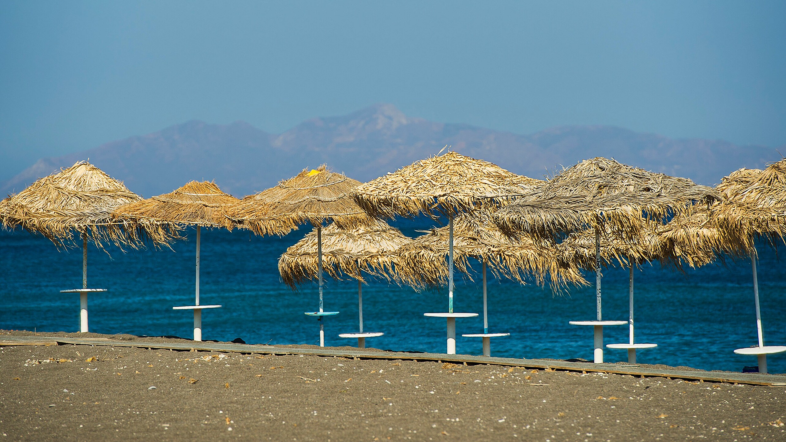 A series of thatched umbrellas on a beach