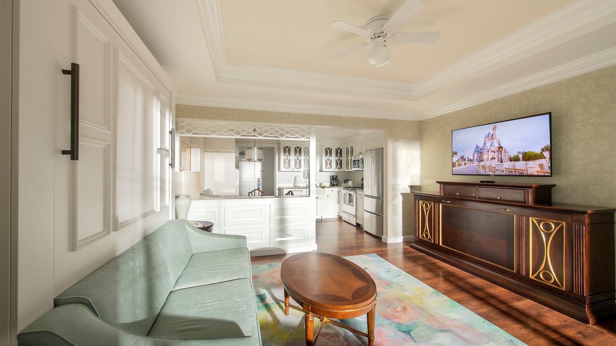 A living room area with a couch, a coffee table and a flat screen television showing an image of Cinderella Castle