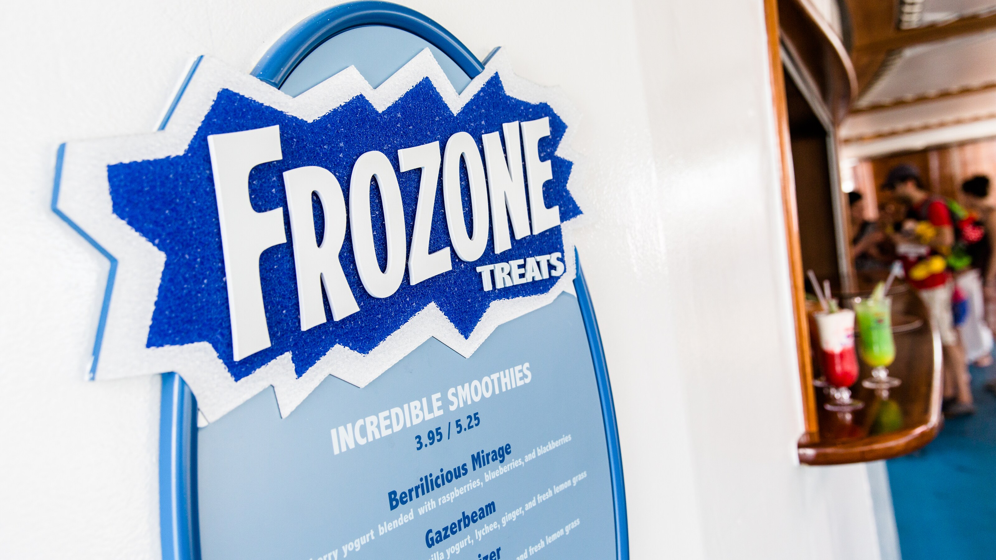Dos bebidas congeladas en un mostrador con un letrero que dice Frozen Treats (golosinas de Frozen) y muestra las opciones de sabrosos batidos