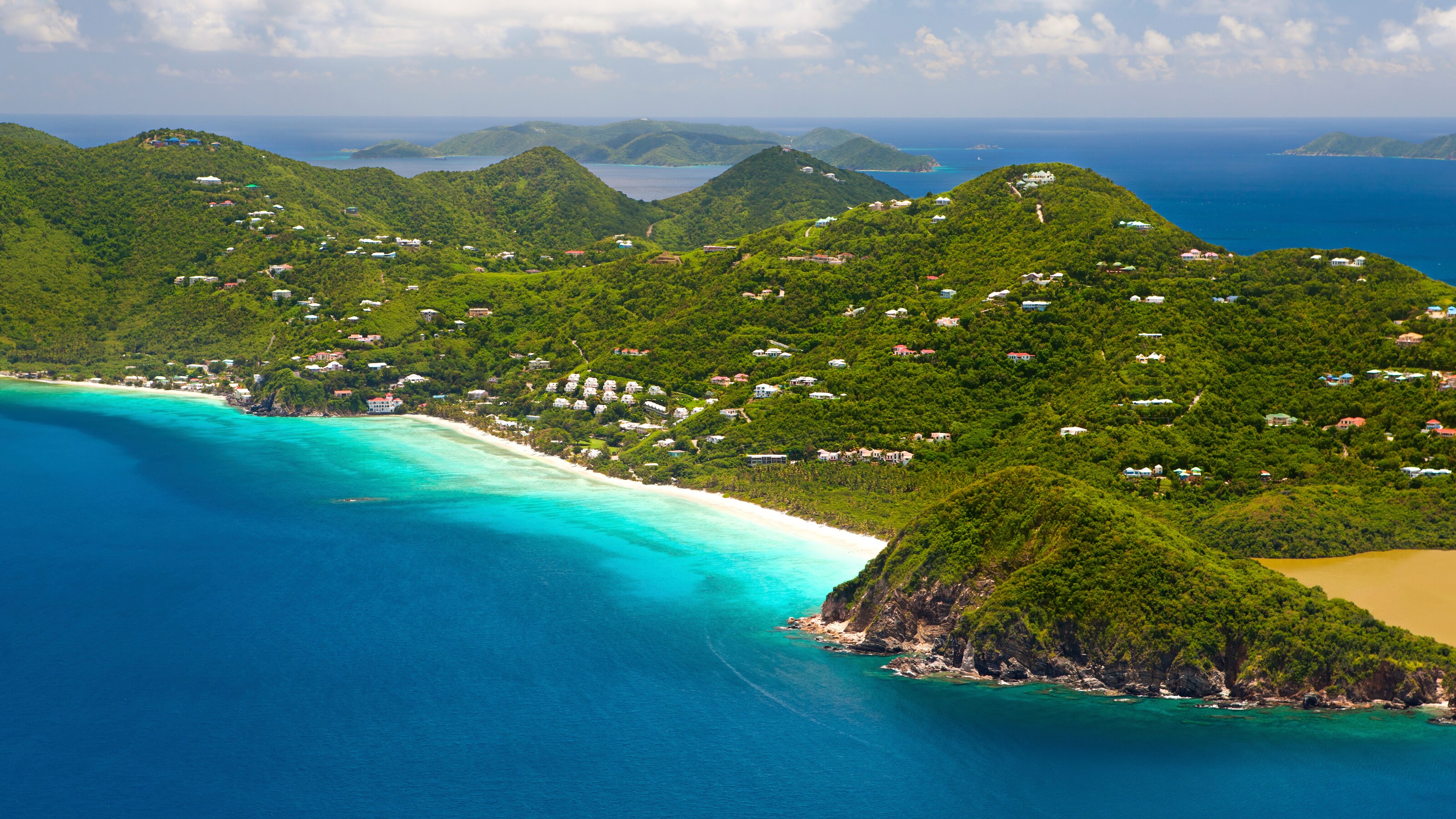 A tropical island features rolling hills blanketed with trees