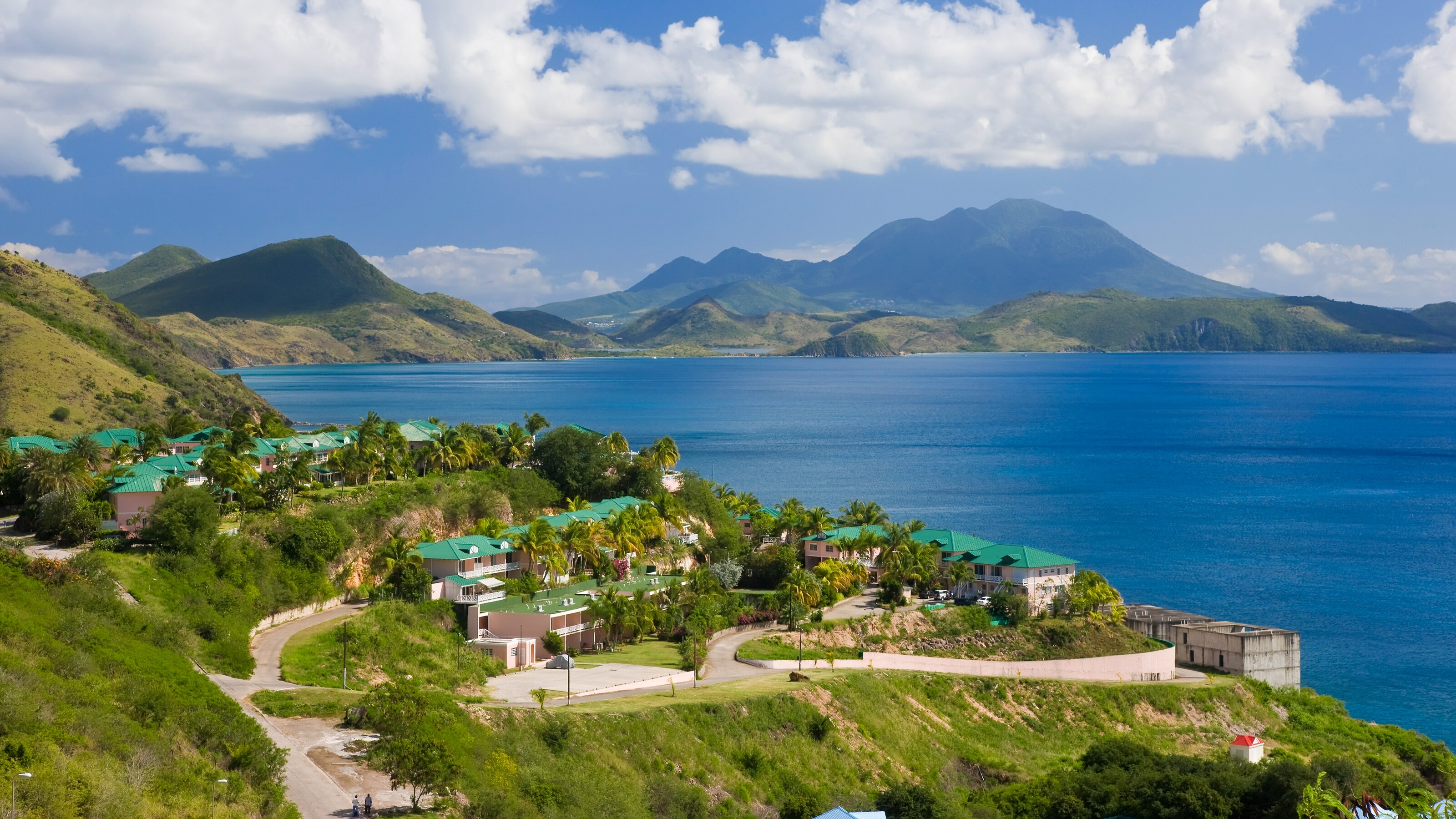 Buildings on a grassy hillside overlooking a beach in St. Kitts