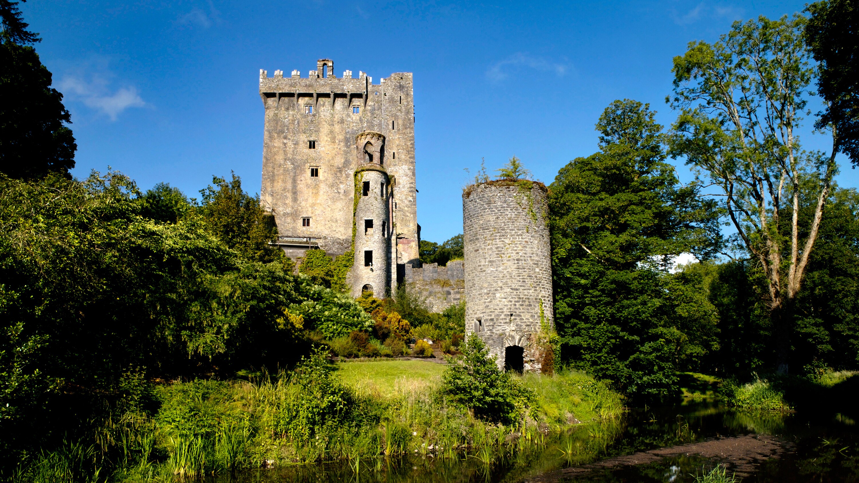 Blarney Castle on the edge of a grassy riverbank