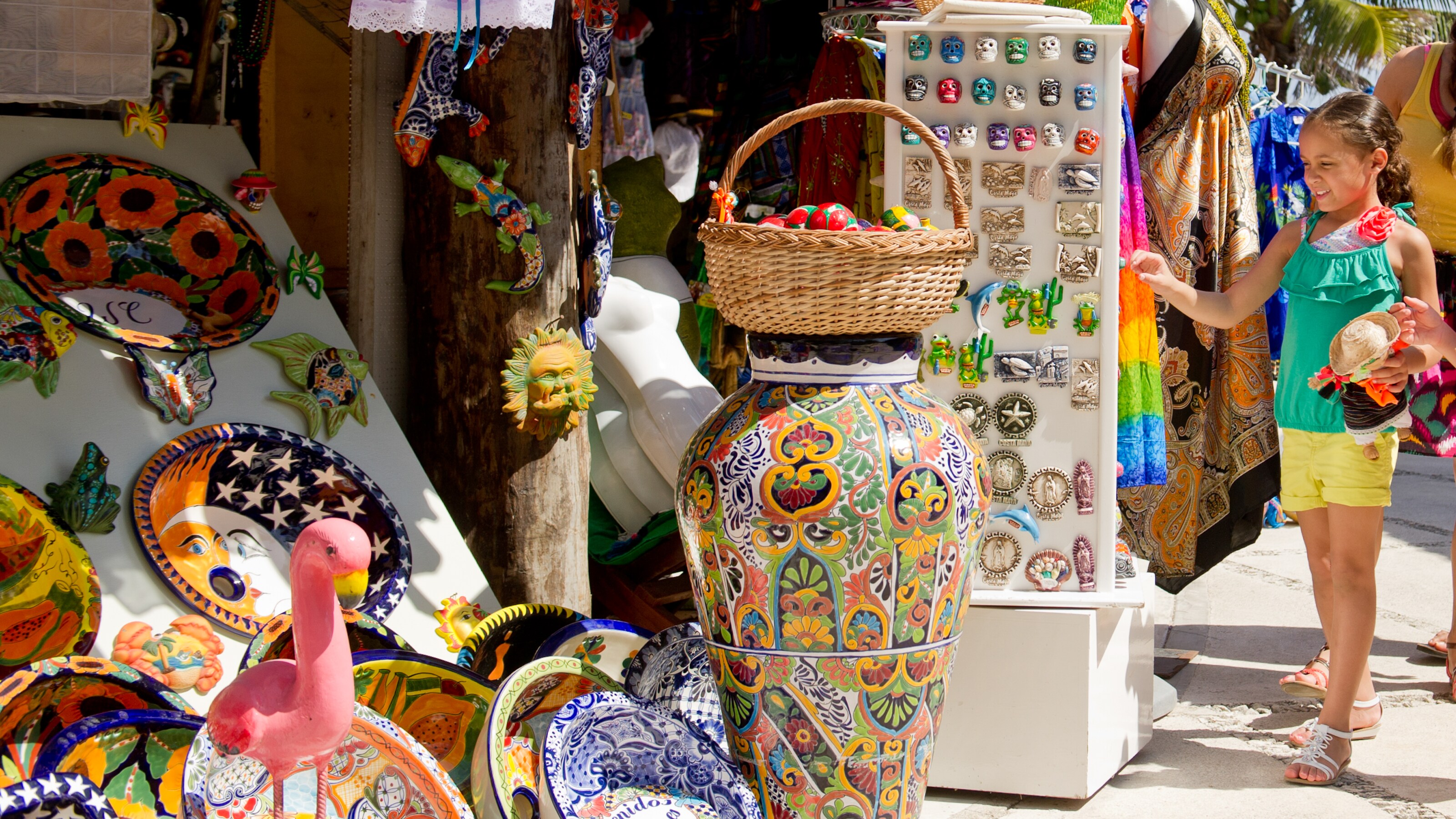 A marketplace for cultural art with pottery, figurines and jewelry is visited by a little girl