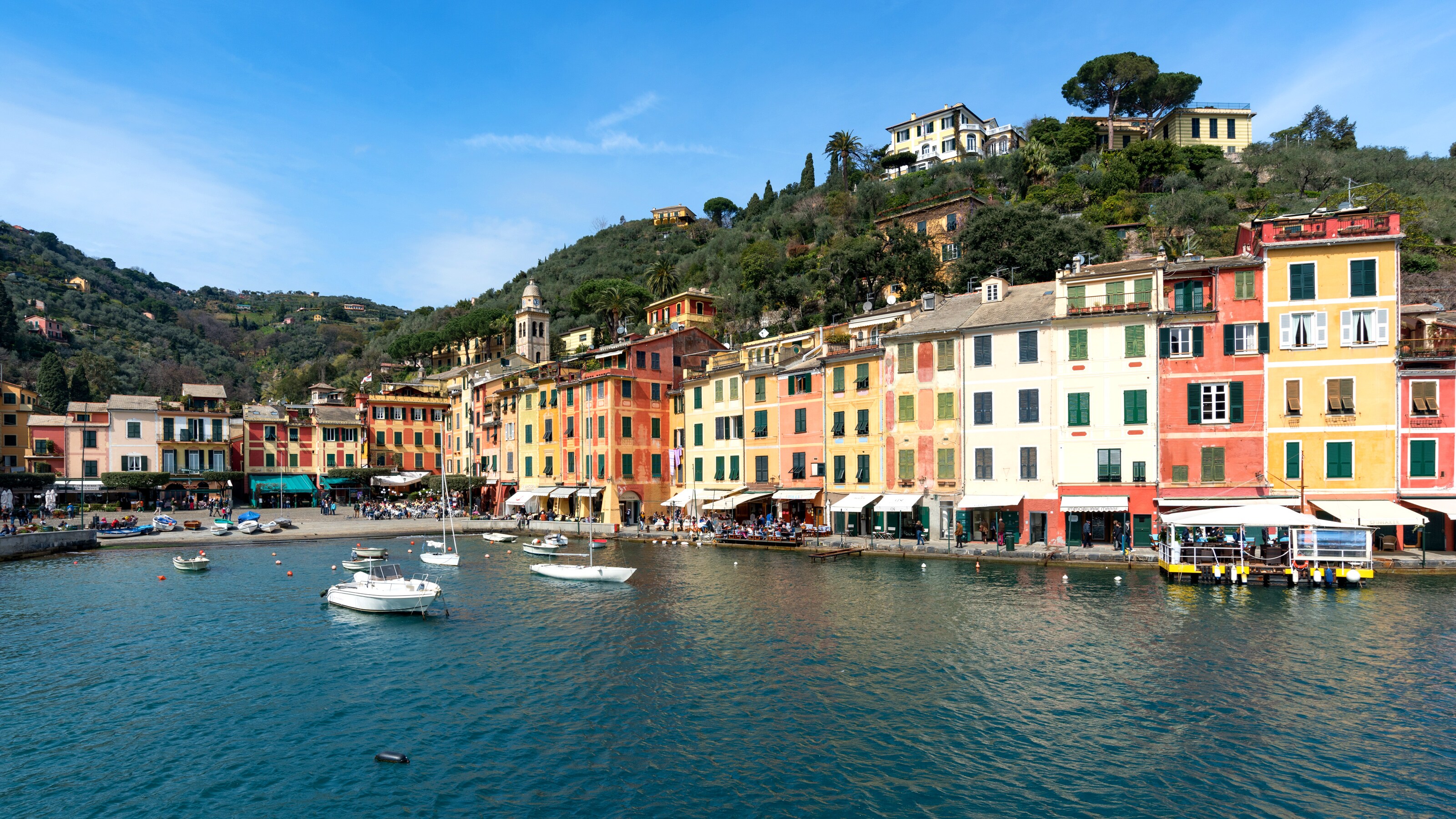Boats on a body of water located next to hills featuring buildings and more