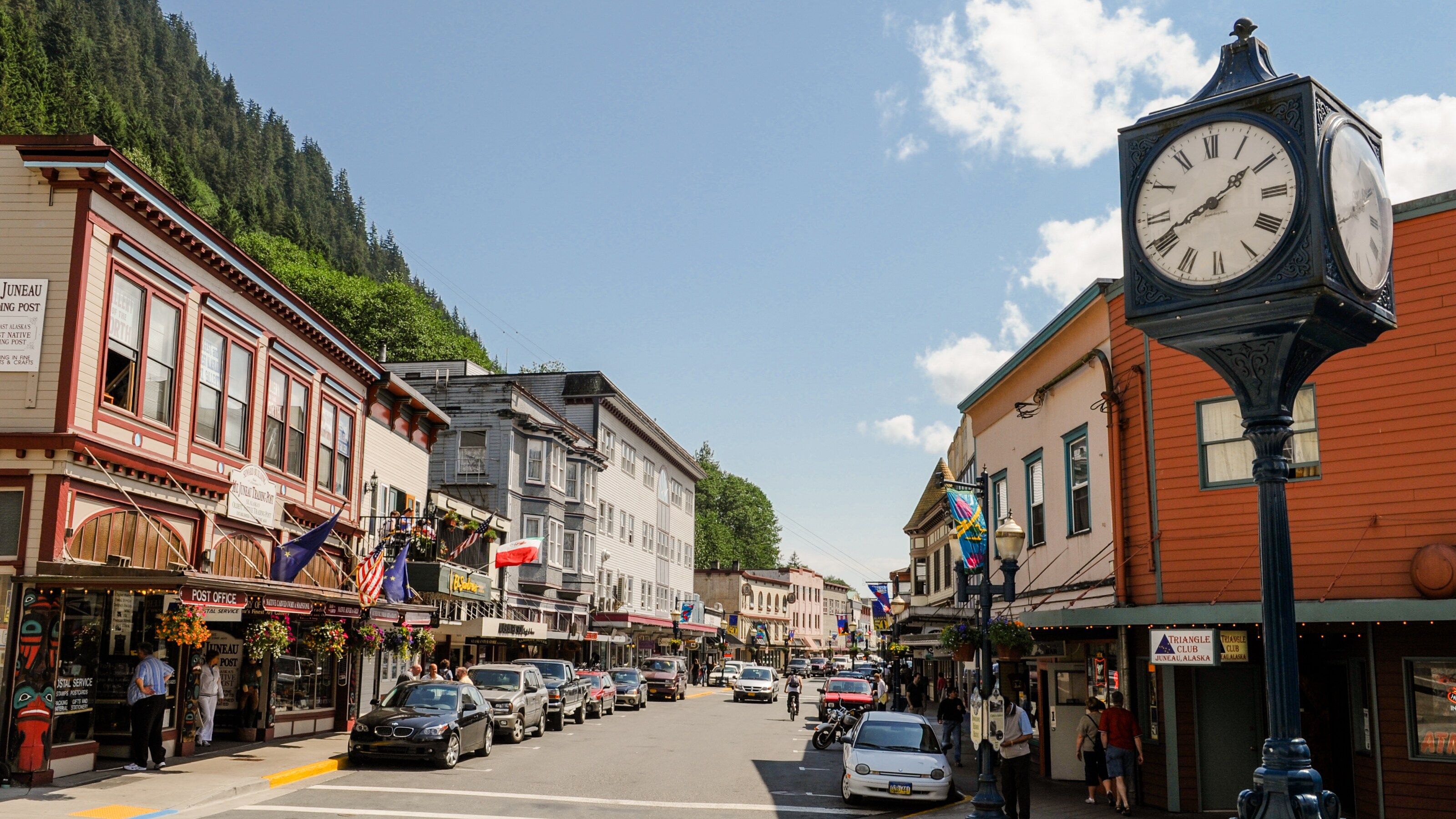 Wood paneled 2 and 3 story builidings with flat rooves line a street with covered sidewalks
