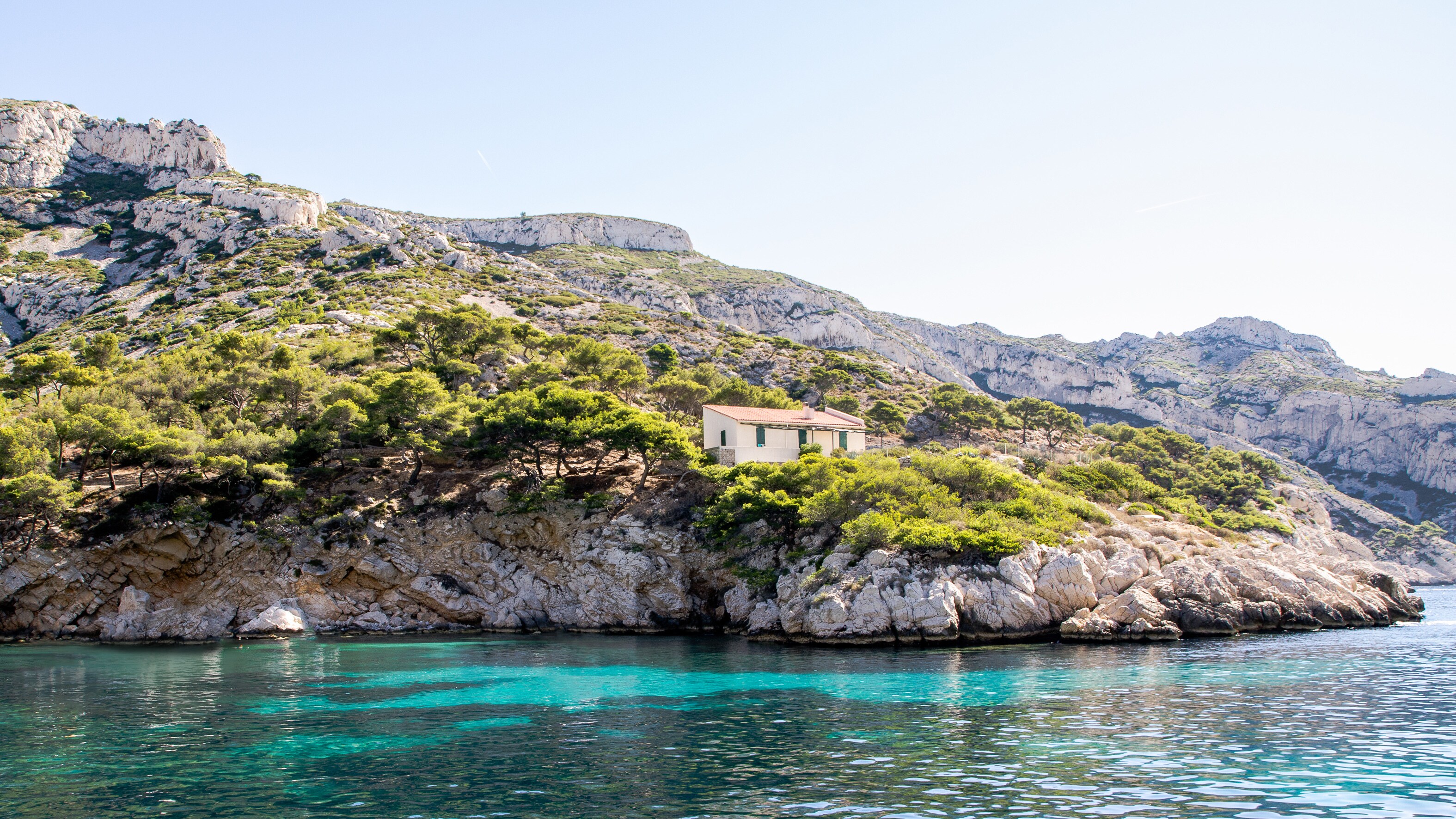A lone home sits on the rocky shores of Marseilles, France, surrounded by lush trees