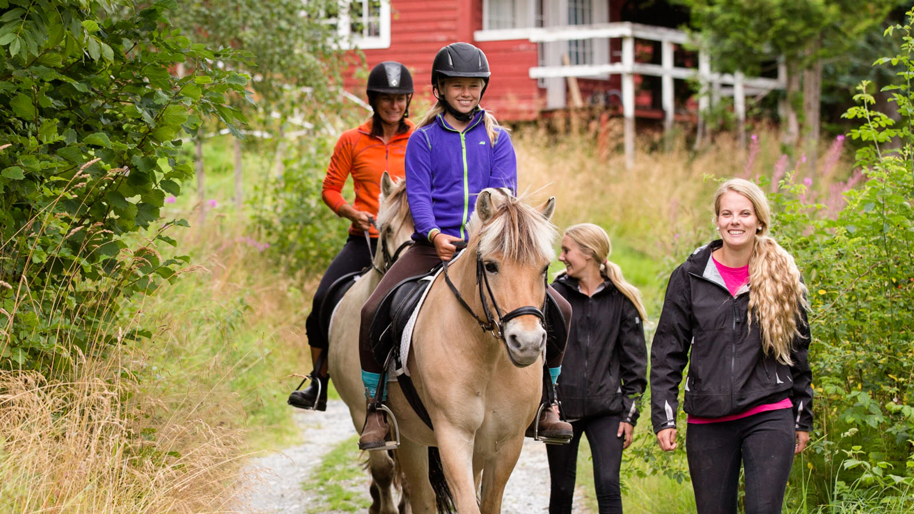 Young girl riding horseback down a trail with 3 other women