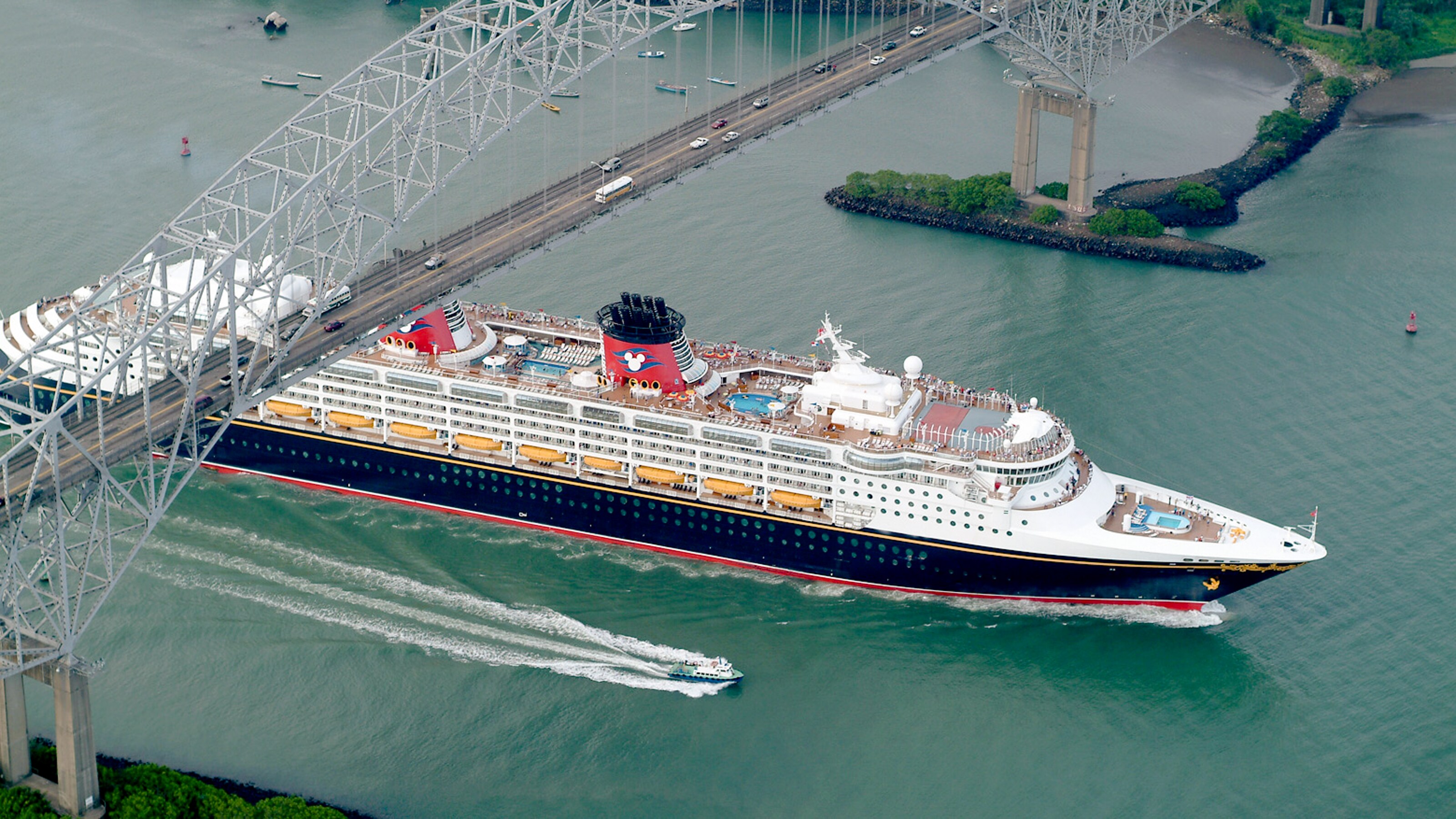 The Disney Wonder passing under a traffic bridge with an arched support system