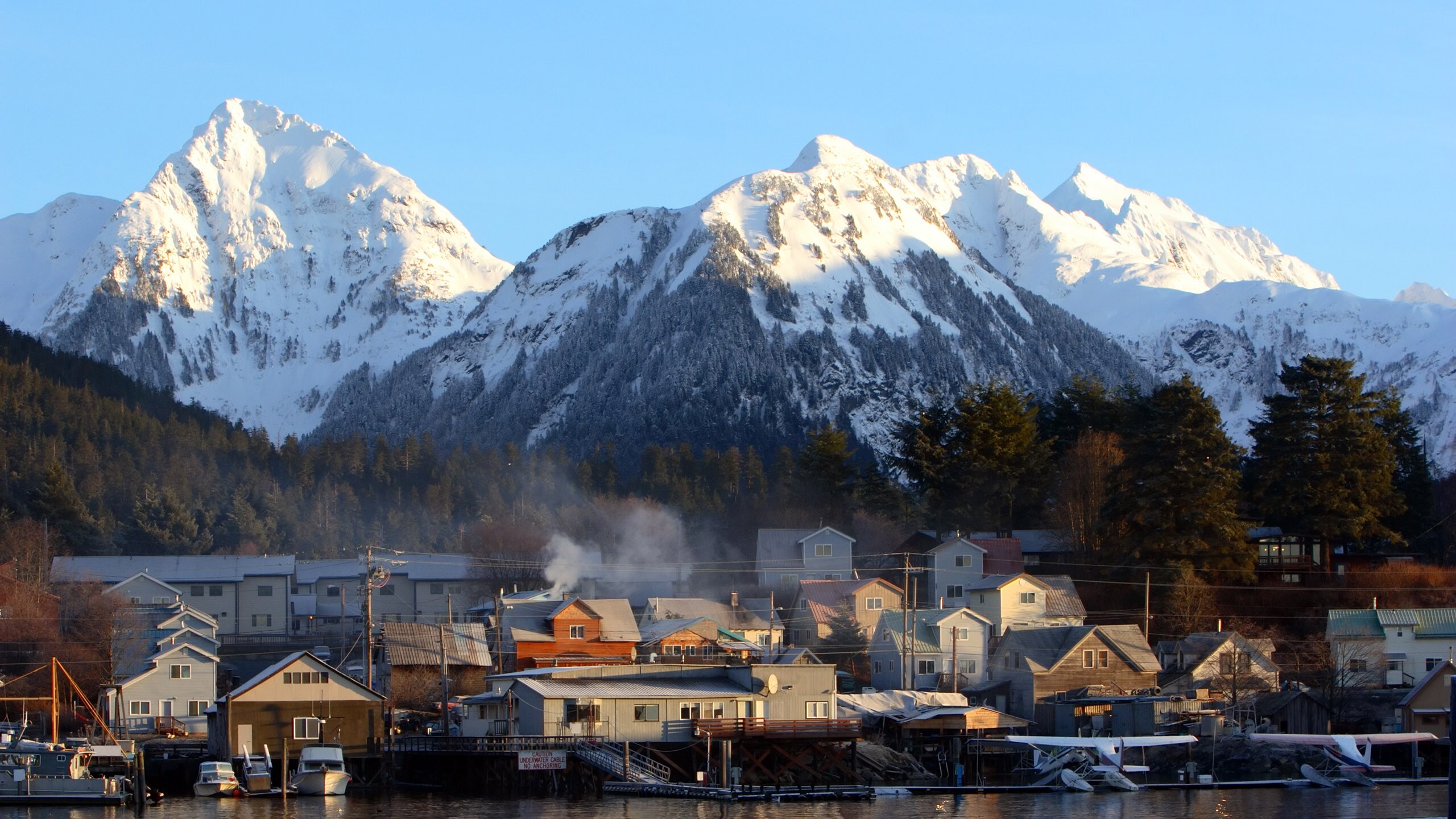 A town near a body of water, a forest and a mountain range