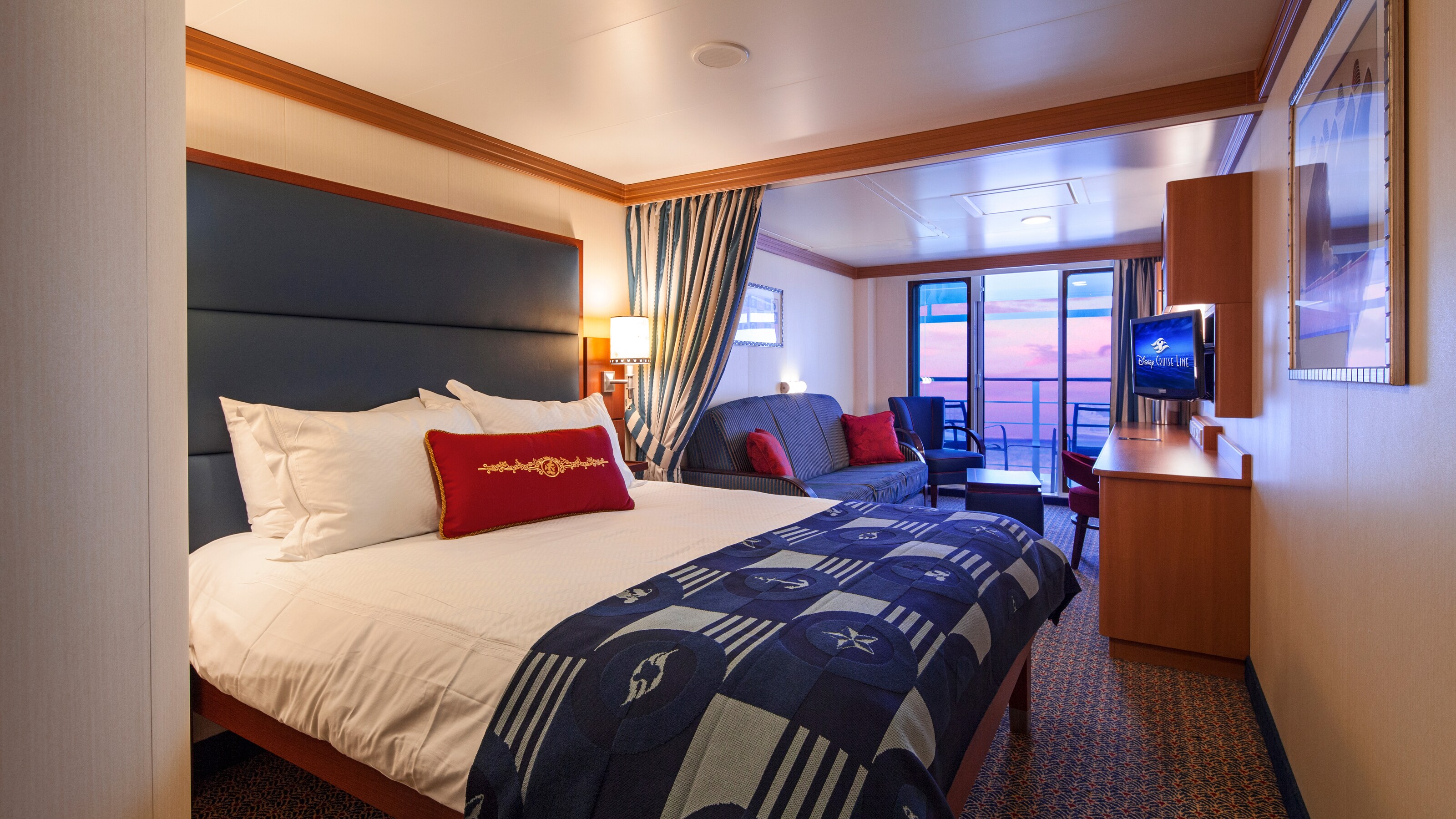 A Disney Cruise Line Deluxe Family Oceanview with Verandah Stateroom with a bed, a sofa, a verandah with an ocean view, a desk and a TV