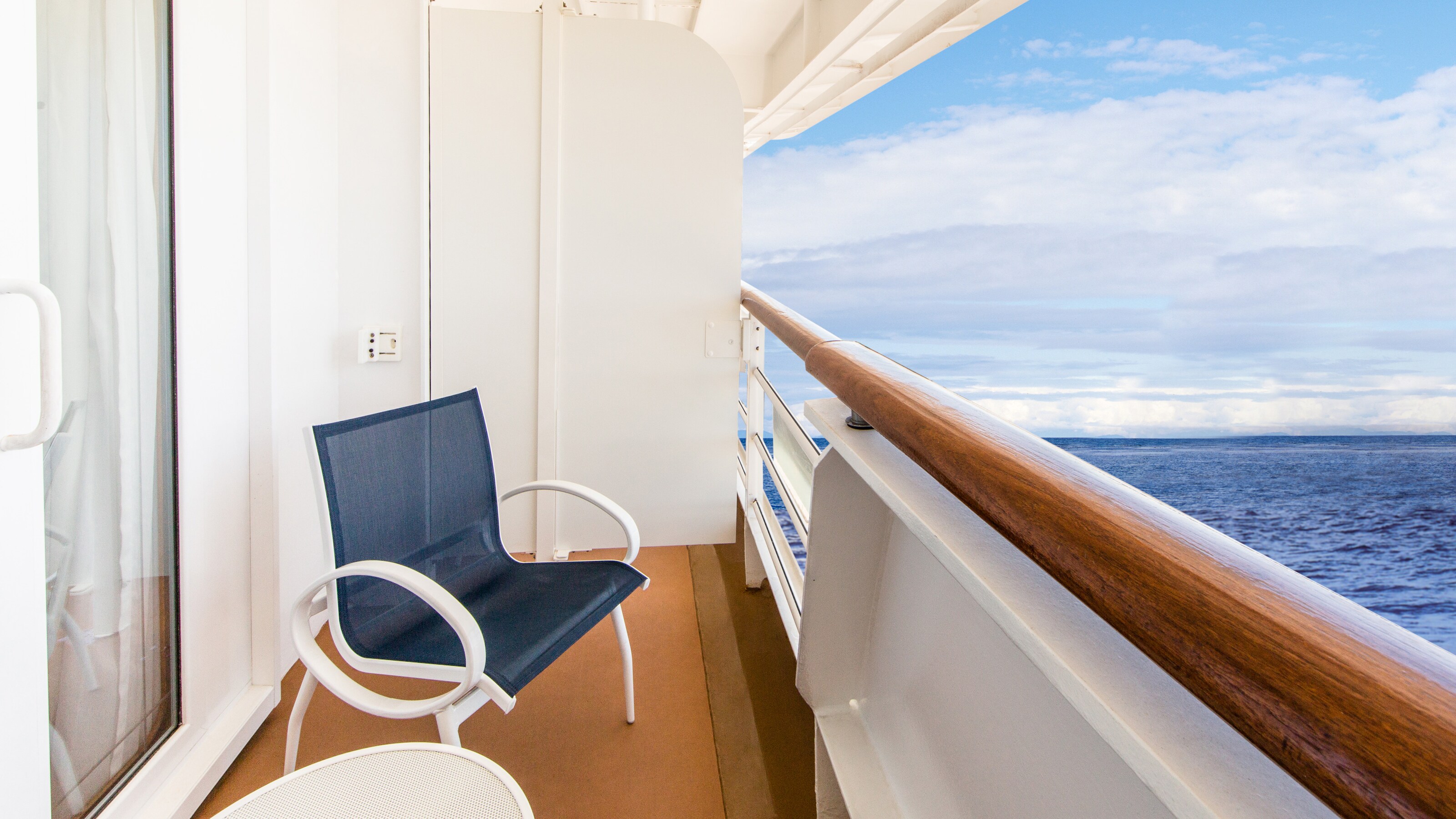A Disney Cruise Line stateroom verandah facing the ocean with a chair and a table