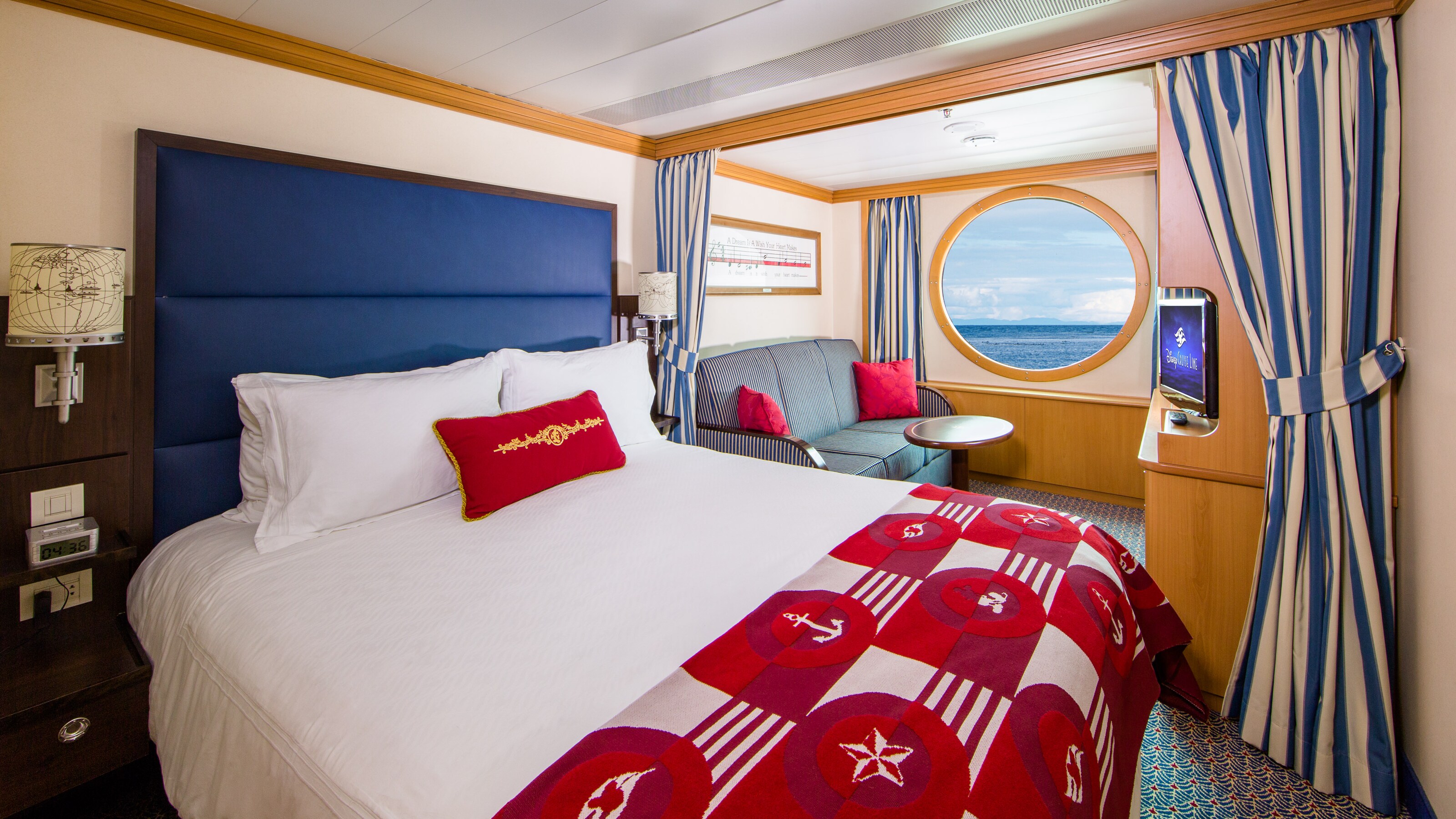 A room with a bed, TV, couch and a window with an ocean view on a Disney Cruise Line ship 
