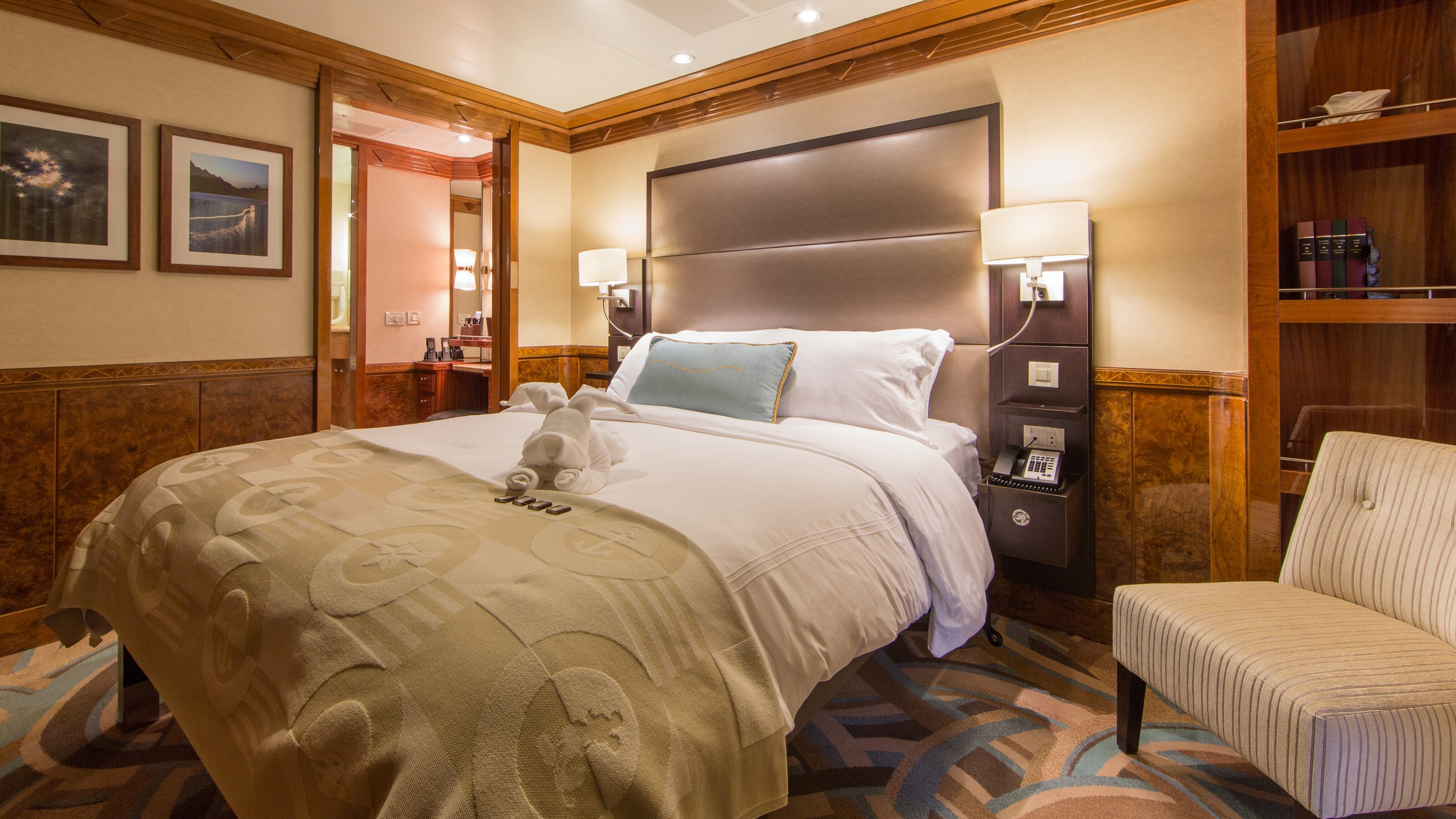 A Disney Cruise Line Concierge Family Oceanview with Verandah Stateroom with a bed, chair, shelves and 2 nightstands