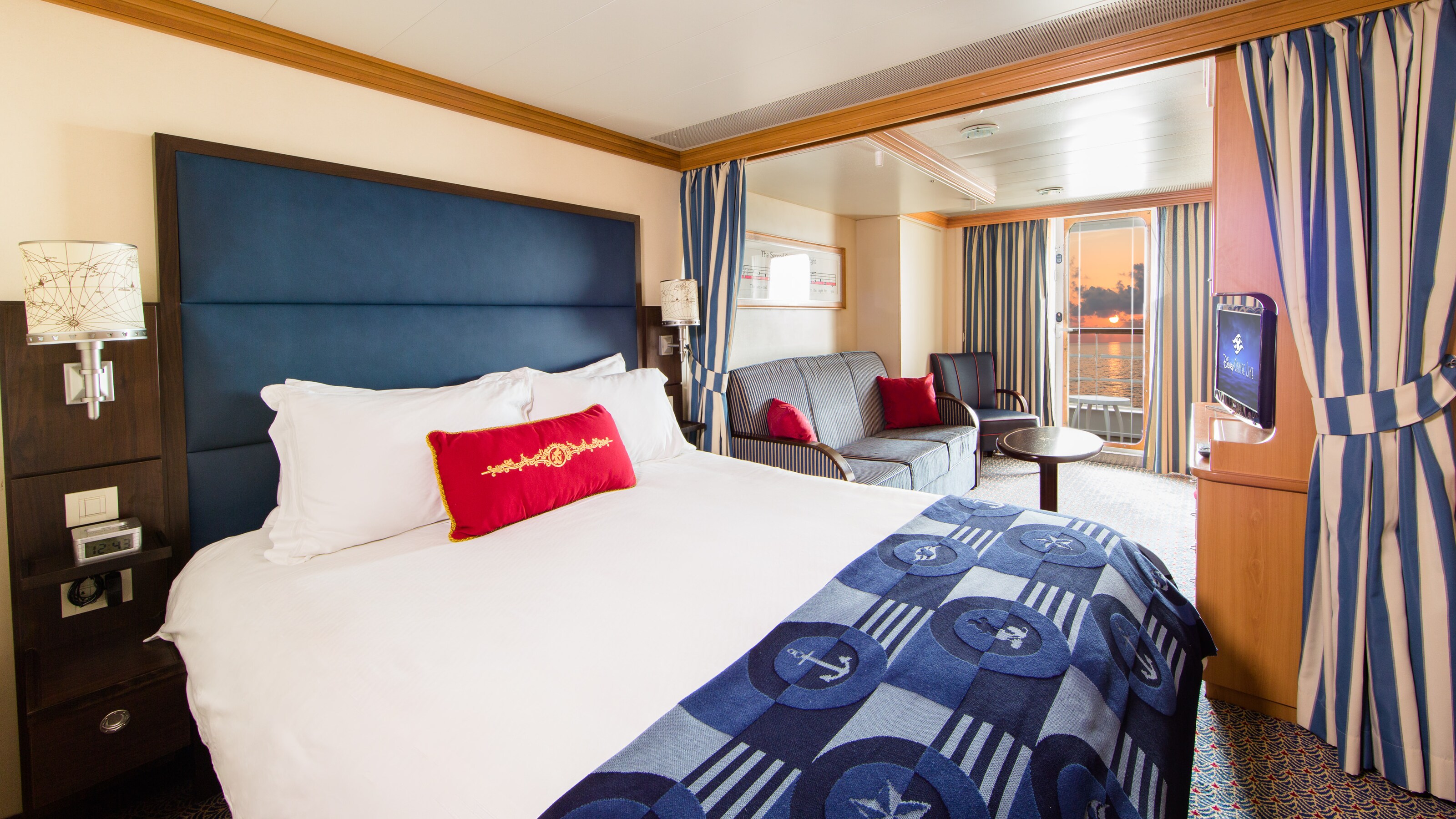 A stateroom with a queen bed, sofa, TV and verandah  