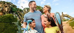 A couple posing with their son, who has a miniature Avatar banshee on his shoulder, and their daughter, who carries an Avatar light up walking stick.
