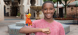 A young boy in the Morocco Pavilion is delighted to pose with the red and blue plumed parrot, Iago, perched on his arm.