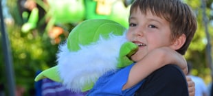 A young boy gets a hug from his sibling who is wearing a Yoda mask.