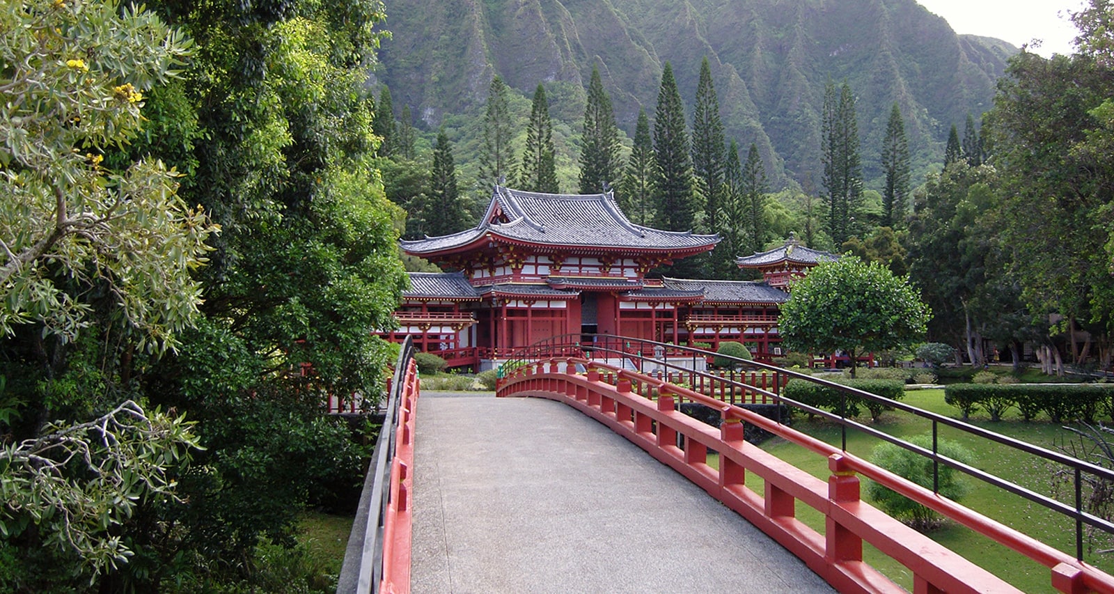 A wooden bridge leading to a temple situated in a verdant valley