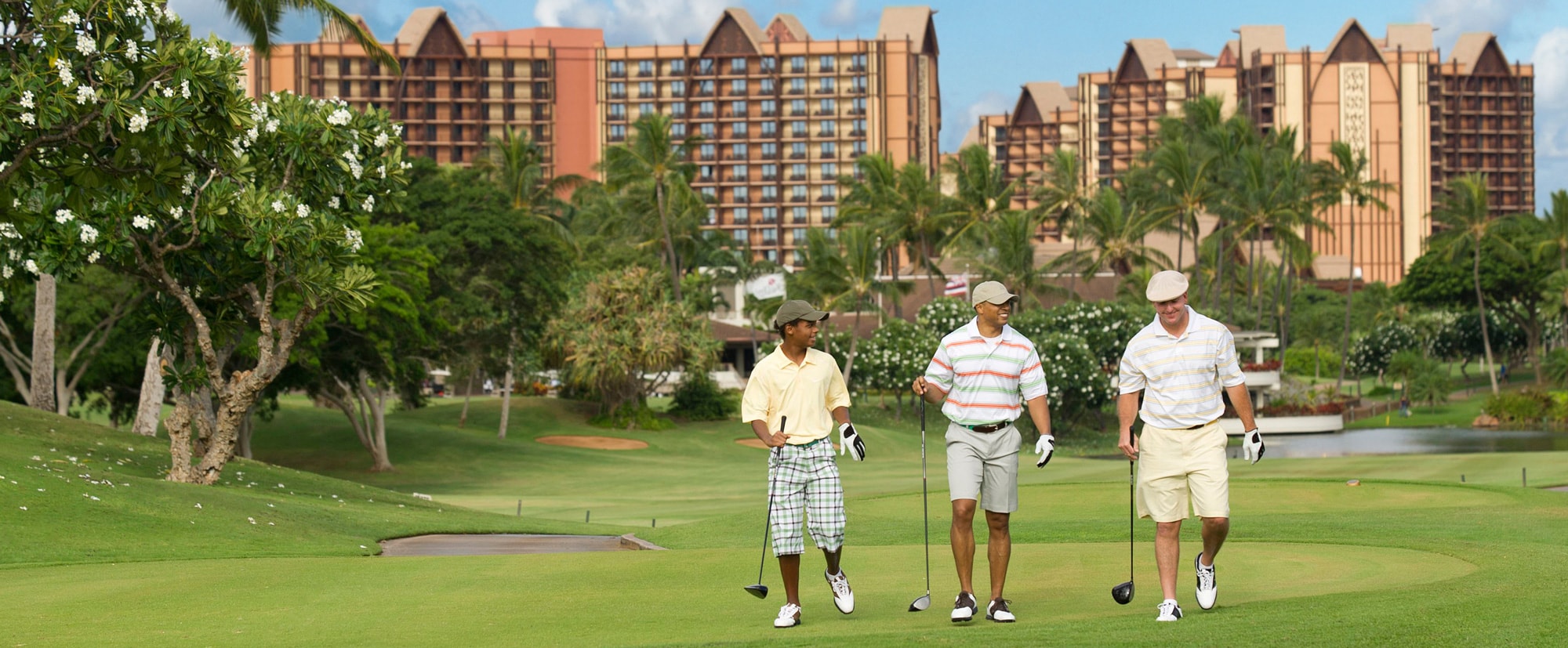 Three men in golf attire walk across the green, each carrying a golf club