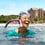 A woman with a snorkel laughing on the sea with the aulani resort on the back