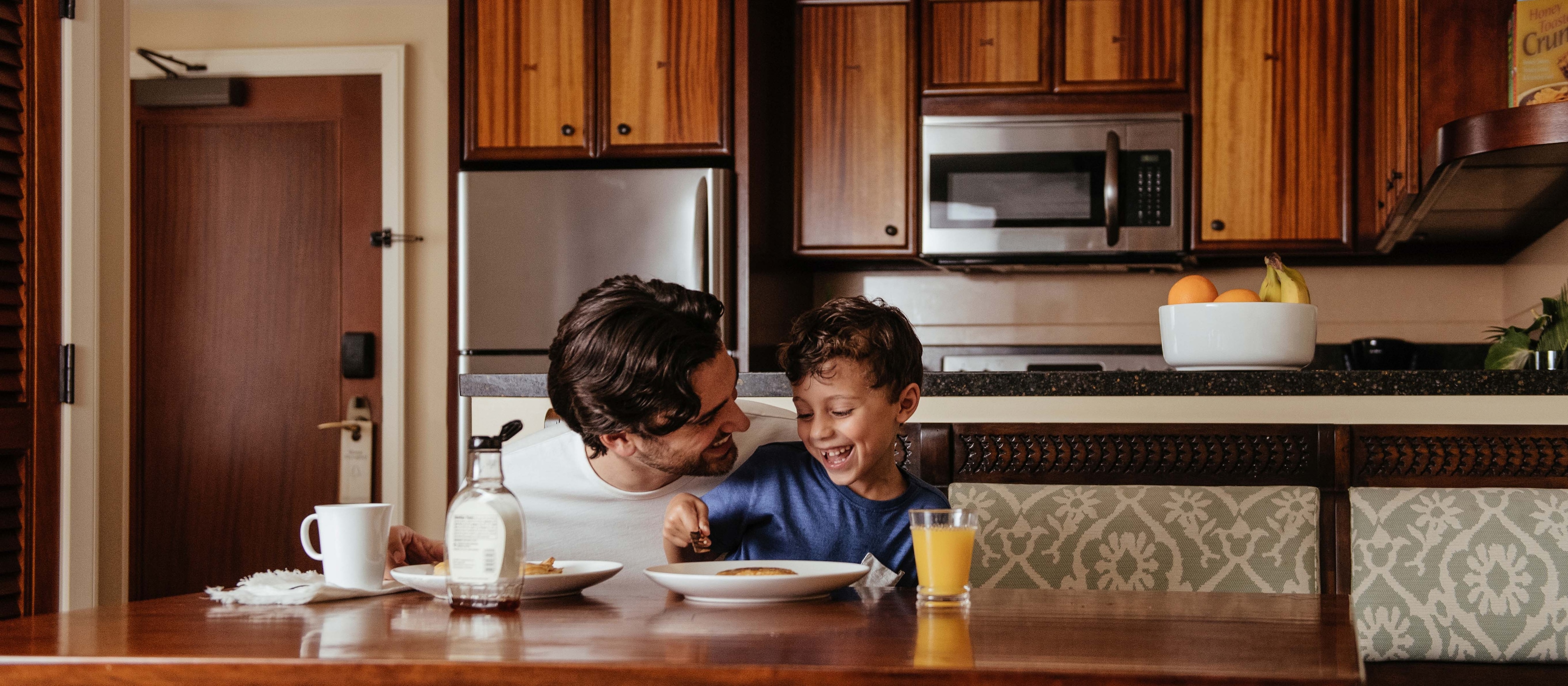 キッチンでホットケーキを食べながら笑い合うお父さんと男の子