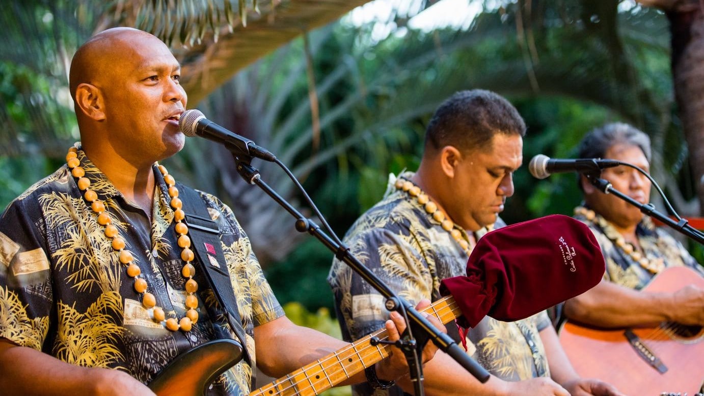 3 musicians dressed in Hawaiian shirts while playing music
