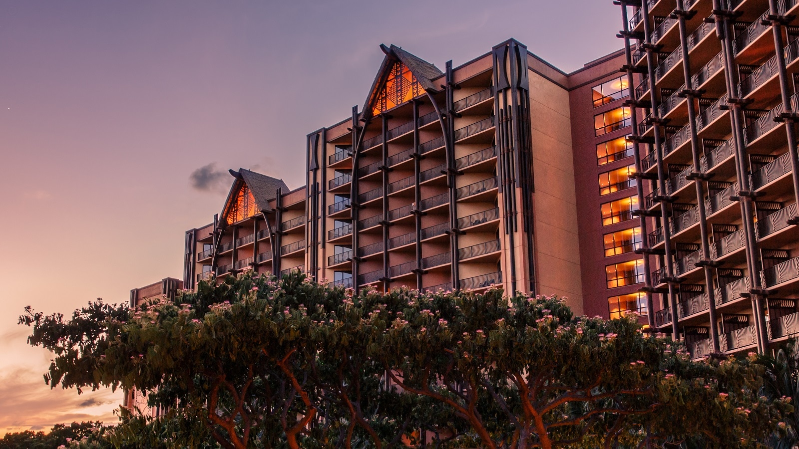 The towers of Aulani Resort & Spa as seen at twilight with a flowering tree in the foreground