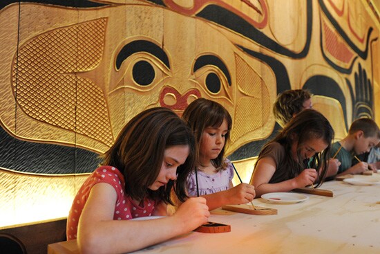 Children paint a wooden feather to add to a special Disney Cruise Line totem pole.