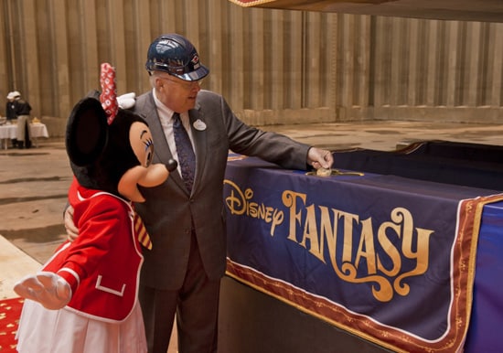 With assistance from Minnie Mouse, Karl Holz, President of Disney Cruise Line, places the coin in the keel for the Disney Fantasy.
