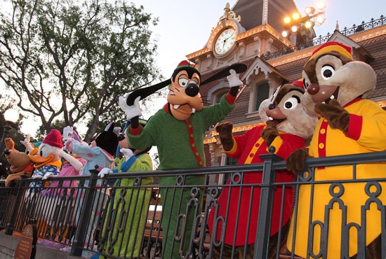 Goofy and his friends in their pajamas atop the Main Street Train Station at Disneyland Park waving goodbye to guests.