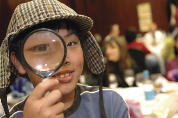 A Young Traveler with Adventures by Disney Looks Through a Magnified Glass