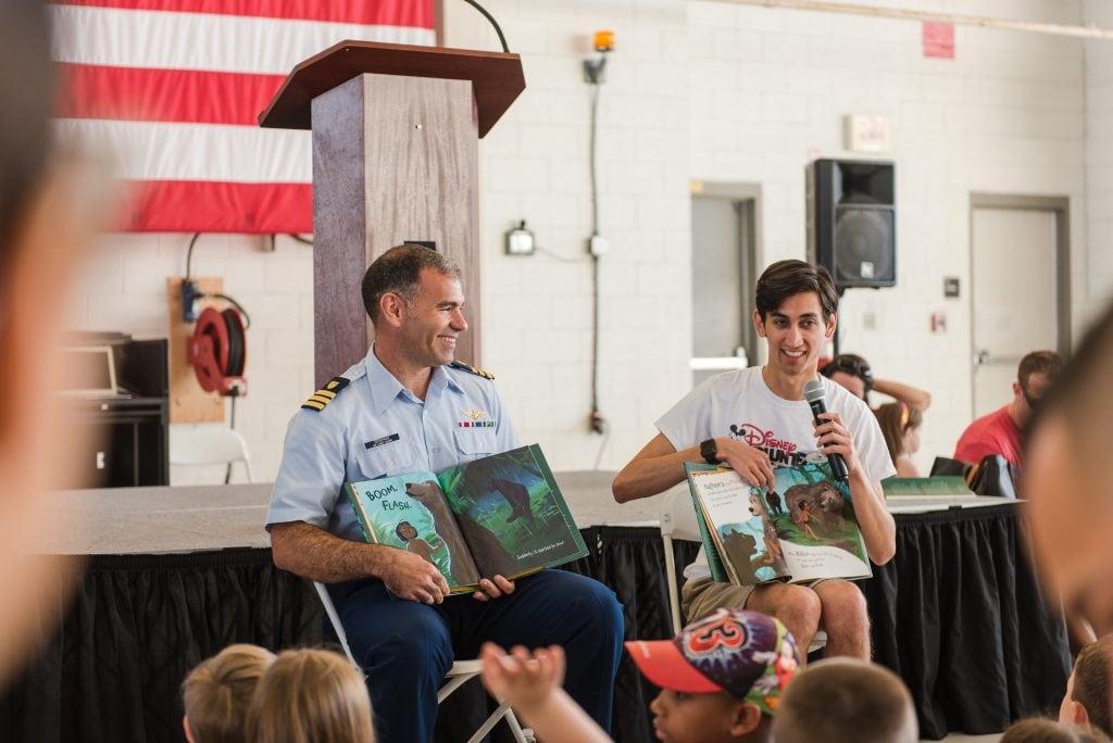 US Coast Guard Executive Officer, Commander Jeffrey Graham and Disney Cruise Line Entertainment Activities Manager Tim Heidorn are all smiles as they read Mowgli’s Rainy Day to children who attended “Books on Bases.”
