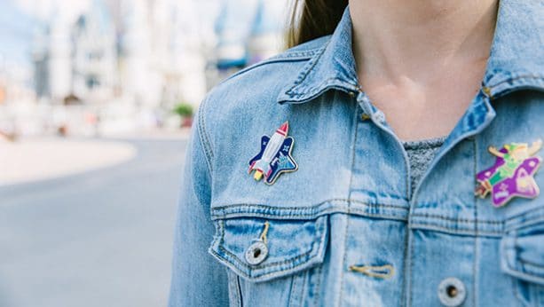 Play Disney Parks wearable achievement pins on a jean jacket