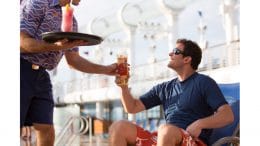 Crew member serving a drink to a guest onboard Disney Cruise Line
