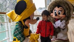Mickey Mouse and Minnie Mouse meet a young guest aboard Disney Cruise Line in Alaska