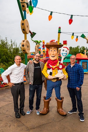 Director Josh Cooley (center left) with Producers Jonas Rivera (left) and Mark Nielsen (right) appear with Woody and Forky (center right) inside Toy Story Land at Disney’s Hollywood Studios