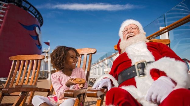 Young guest sits with Santa Claus aboard Disney Cruise Line