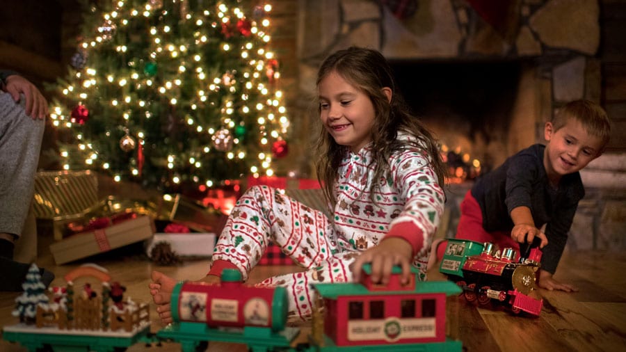 Children wearing holiday merchandise and playing with toy train set