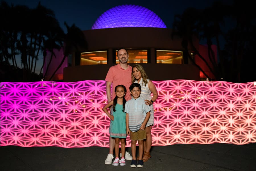 Family poses at Disney PhotoPass location in Future World near Spaceship Earth at Epcot