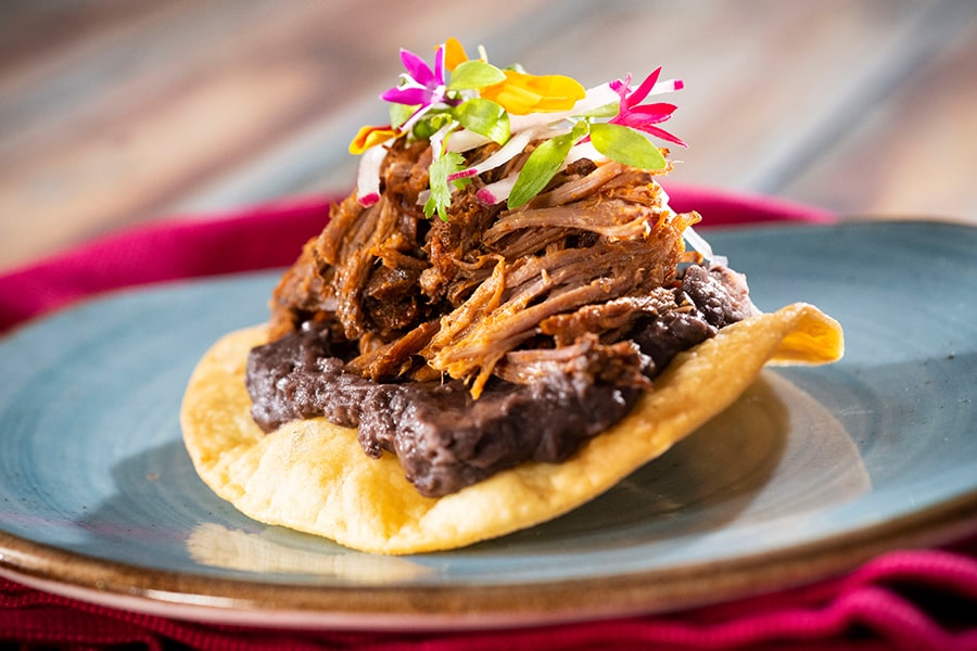 Foodie Guide to the 2020 Taste of EPCOT International Food & Wine Festival – Opening Today Offerings from Mexico Marketplace for the 2020 Epcot Taste of International Food & Wine Festival - Pork Tostada: Fried Corn Tortilla topped with Chipotle Black Beans, Roasted Pork, Fresh Salsa Verde, Onions, and Cilantro 