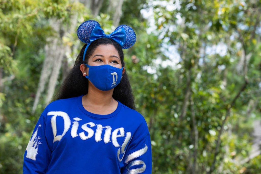 Girl in the new Wishes Come True Blue Minnie Mouse Ear headband, mask and spirit jersey with Disneyland Resort logo
