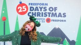 Guest in front of Freeform's ’25 Days of Christmas’ Photo Wall at Disney Springs
