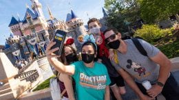 Guests take a selfie in front of Sleeping Beauty Castle at Disneyland park