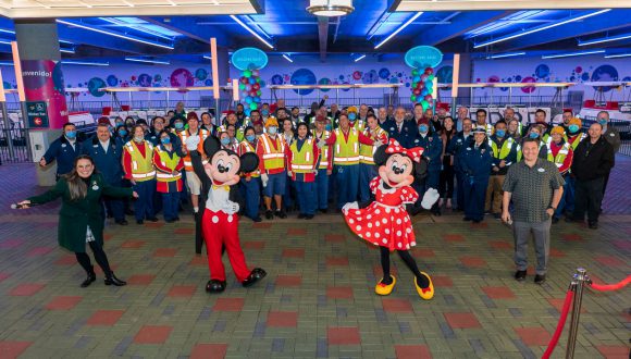 Mickey Mouse, Minnie Mouse and smiling cast members in front of a Disneyland Resort parking tram