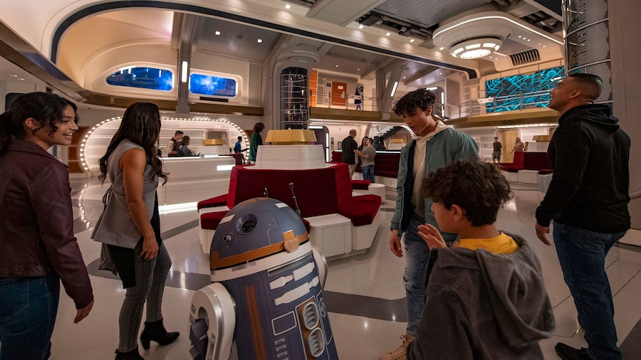 Astromech droid SK-62O greets guests in the Atrium of the Halcyon starcruiser in Star Wars: Galactic Starcruiser at Walt Disney World Resort