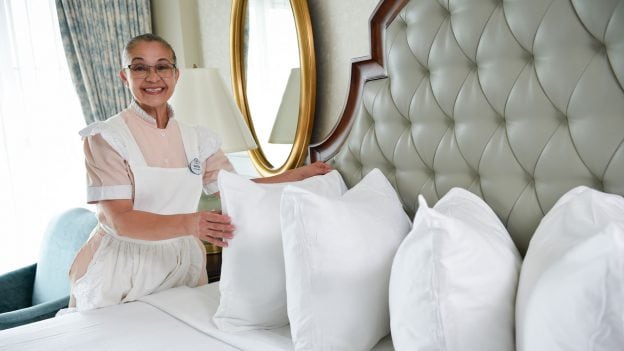 Housekeeping cast member Martha places a bed pilow in a Disney resort room