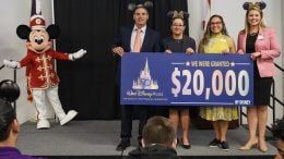 Cast members and Mickey Mouse granting a check